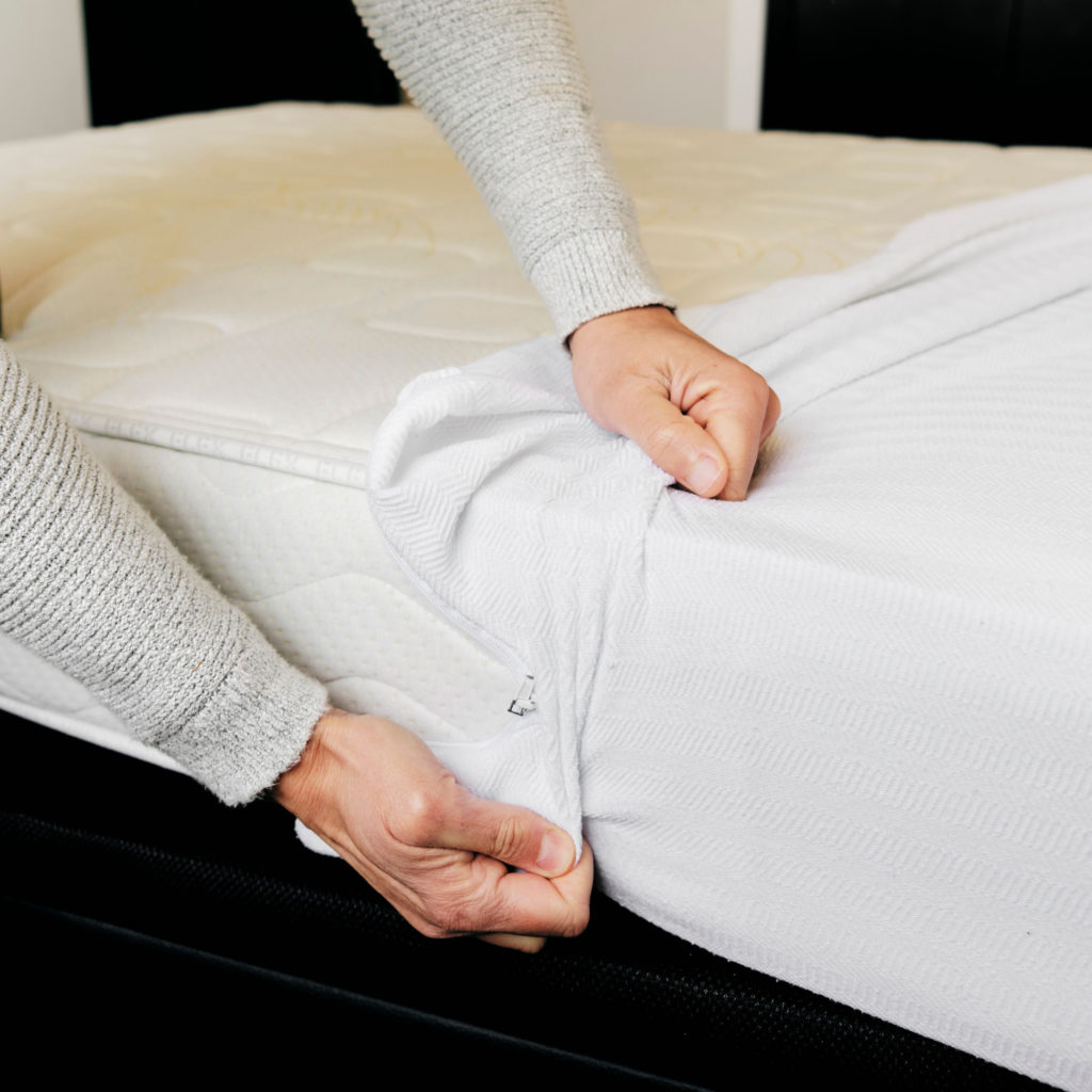 Do You Need a Mattress Protector? Man installs a mattress protector