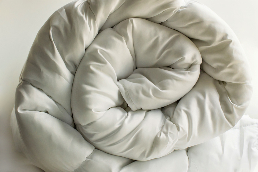 Down vs. Down Alternative Comforters Soft white down comforter rolled on a white background
